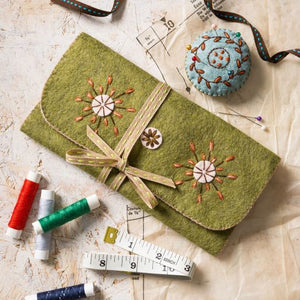 Green felt case with floral embroidery on a textured surface with sewing supplies. Designed by Corinne Lapierre. Available at tinypatio.com