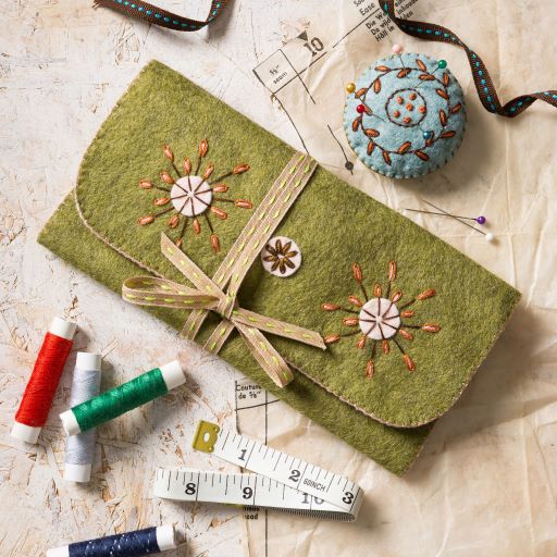 Green felt case with floral embroidery on a textured surface with sewing supplies. Designed by Corinne Lapierre. Available at tinypatio.com