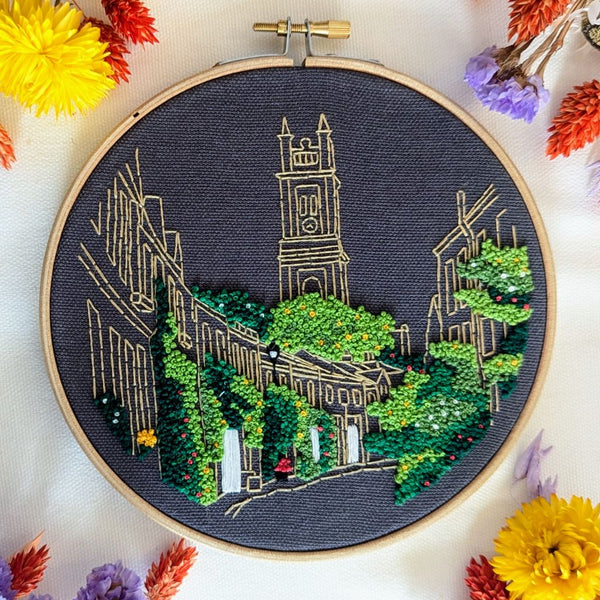 Finished Circus Lane embroidery in a 6 inch hoop, Edinburgh cottages in gold outline with dense green foliage on charcoal fabric