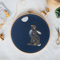 Finished moon gazing hare embroidery in an 8 inch hoop, stitched in gold and cream on navy with a white moon above