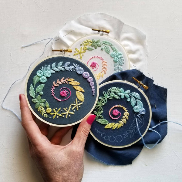 Jessica Long Spiral Sampler beginner embroidery kit on navy fabric. Learn 14 essential embroidery stitches with step-by-step video guidance. Includes printed navy fabric, 10 cm (4") hoop, DMC thread & instructions.