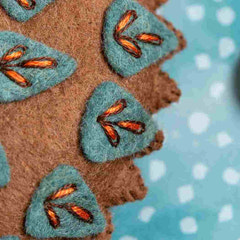 Close-up of brown fabric with embroidered green leaves on a polka dot background. Designed by Corinne Lapierre. Available at tinypatio.com
