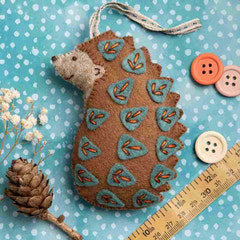Felt hedgehog ornament with teal pattern on a blue polka dot background with buttons and a ruler. Designed by Corinne Lapierre. Available at tinypatio.com