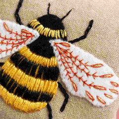Embroidered bee with black, yellow, and white colors on fabric.