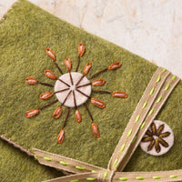 Green fabric pouch with embroidered design on a textured surface. Designed by Corinne Lapierre. Available at tinypatio.com