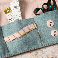 Felt sewing roll, ribbon, and measuring tape on a light background. Designed by Corinne Lapierre. Available at tinypatio.com