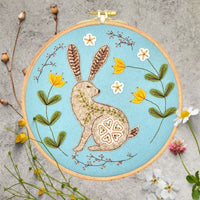 Wild Hare Applique Felt Kit with a rabbit design surrounded by flowers on a textured surface. By Corinne Lapierre. Available at tinypatio.com