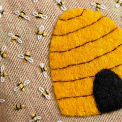 Felt bee hive with bees on a textured brown background