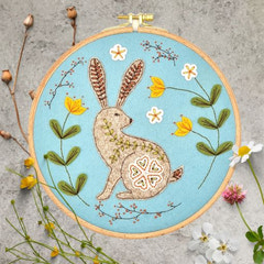 Wild Hare Applique Felt Kit with a rabbit design surrounded by flowers on a textured surface. By Corinne Lapierre. Available at tinypatio.com