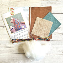 Felt kit with fabric samples, thread, and a pattern book on a wooden surface. Designed by Corinne Lapierre. Available at tinypatio.com