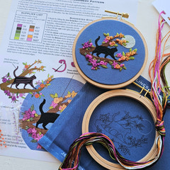 Embroidery hoops with cat and floral designs on a printed instruction. This is a beginner embroidery kit by Jessica Long, designed for adults.