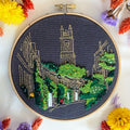 Finished Circus Lane embroidery in a 6 inch hoop, Edinburgh cottages in gold outline with dense green foliage on charcoal fabric