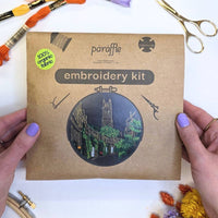 Hands holding the Paraffle kraft kit envelope printed with the Circus Lane design