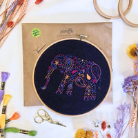 Paraffle kraft kit envelope with the completed elephant hoop on top, DMC thread bundles and embroidery scissors alongside