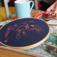The finished elephant hoop on a table beside a blue mug and a slice of cake