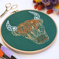 The Highland coo hoop tilted to show the raised orange fringe and cream horns in stranded cotton