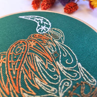Macro close-up of the coo's orange paisley fringe stitching filling the green fabric