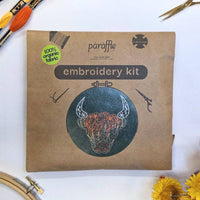 The Paraffle kraft kit envelope printed with the Highland coo design, flat on white with an organic fabric sticker