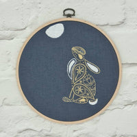 The moon gazing hare hoop hung on a white painted brick wall by a metal hanger