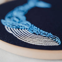 Close-up of the whale's cream belly rows and swirling blue paisley body stitched in stranded cotton