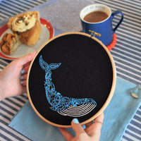 Someone holding the finished whale hoop at a table laid with coffee and cake