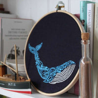 The whale hoop standing on a shelf between books and a glass bottle